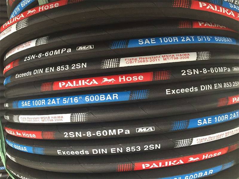 It shows a pile of SAE 100R2 steel wire reinforced hydraulic hoses with marks on them.