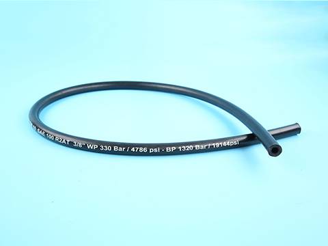 There is a coil of steel wire reinforced hydraulic hose displayed on blue background.