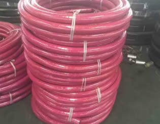 Many rolls of steam hoses are on the floor of the warehouse.